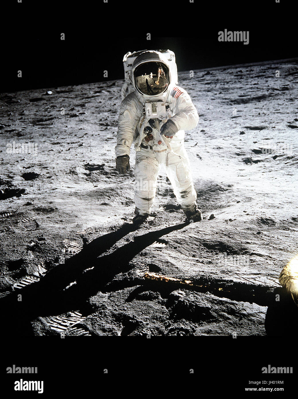 Astronaut Buzz Aldrin, lunar module pilot of the first lunar landing mission, poses for a photograph with the deployed United States flag reflected in his visor during an Apollo 11 Extravehicular Activity (EVA) on the lunar surface. The Lunar Module (LM) is on the left, and the footprints of the astronauts are clearly visible in the soil of the Moon. Astronaut Neil A. Armstrong, commander, took this picture with a 70mm Hasselblad lunar surface camera. Photograph by Neil A. Armstrong / NASA Stock Photo