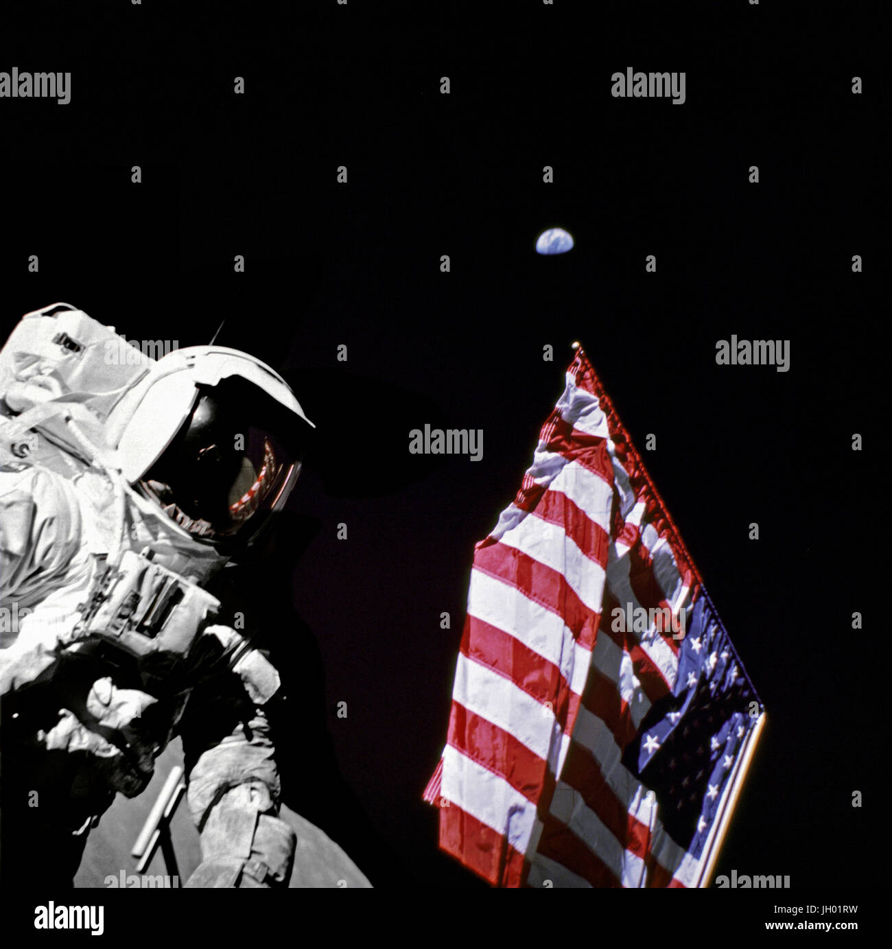 Geologist-Astronaut Harrison Schmitt, Apollo 17 Lunar Module pilot, is photographed next to the American Flag during extravehicular activity (EVA) of NASA's final lunar landing mission in the Apollo series. The photo was taken at the Taurus-Littrow landing site. The highest part of the flag appears to point toward our planet earth in the distant background. Photographer: NASA / Eugene Cernan Stock Photo