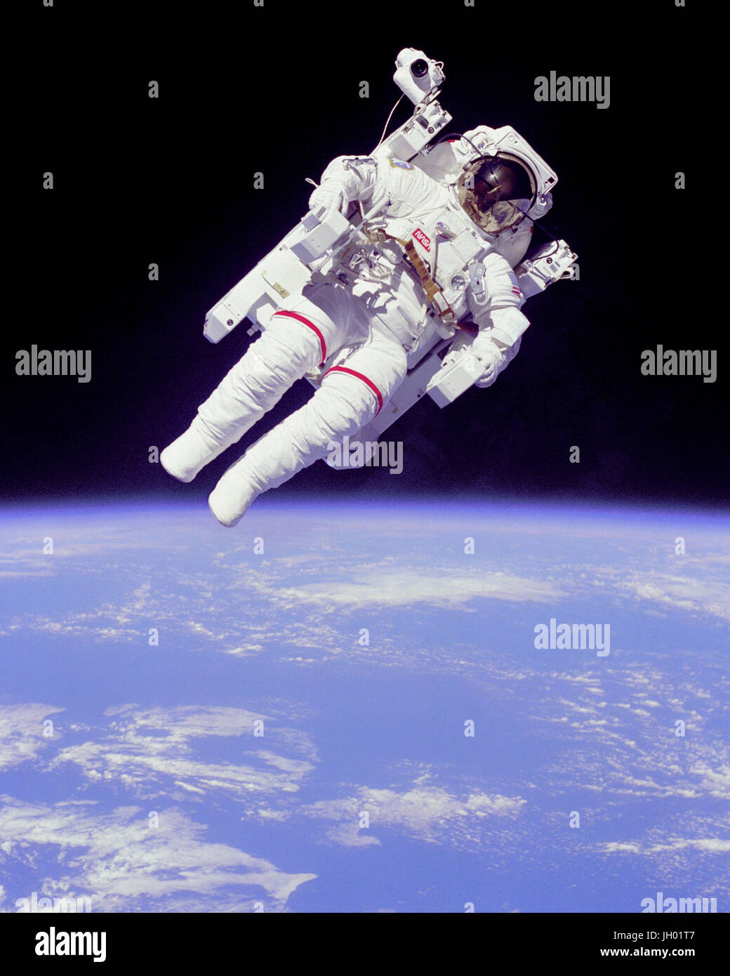'Backpacking'.Full Description.Mission Specialist Bruce McCandless II ventured further away from the confines and safety of his ship than any previous astronaut ever has. This space first was made possible by the Manned Manuevering Unit or MMU, a nitrogen jet propelled backpack. After a series of test maneuvers inside and above Challenger's payload bay, McCandless went 'free-flying' to a distance of 320 feet away from the Orbiter. The MMU is controled by joy sticks positioned at the end of the arm rests. Moving the joy sticks left or right or by pulling them fires nitrogen jet thrusters propel Stock Photo