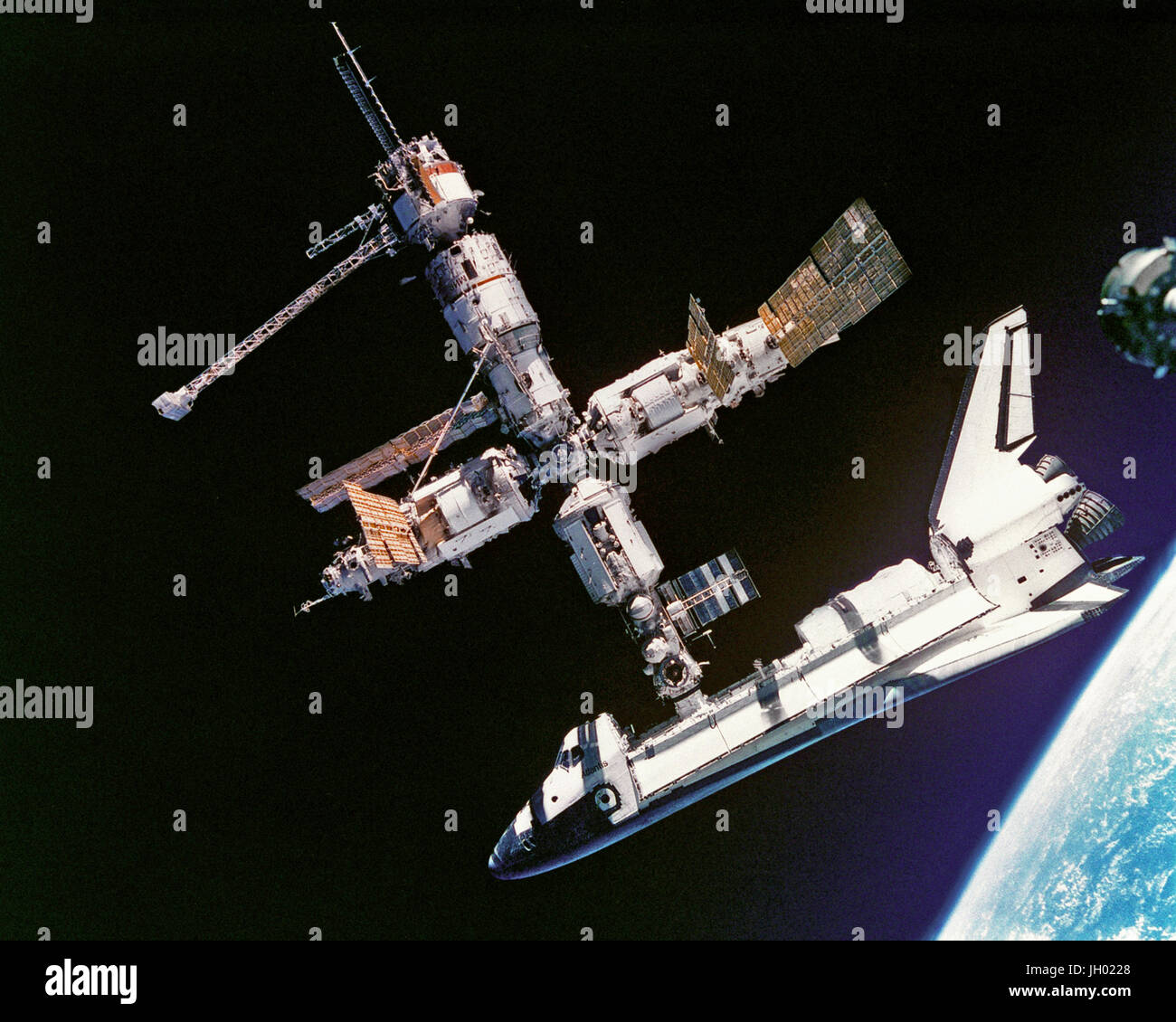 This view of the Space Shuttle Atlantis still connected to Russia's Mir Space Station was photographed by the Mir-19 crew on July 4, 1995. Cosmonauts Anatoliy Y. Solovyev and Nikolai M. Budarin, Mir-19 Commander and Flight Engineer, respectively, temporarily undocked the Soyuz spacecraft from the cluster of Mir elements to perform a brief fly-around. They took pictures while the STS-71 crew, with Mir-18's three crew members aboard, undocked Atlantis for the completion of this leg of the joint activities. Stock Photo