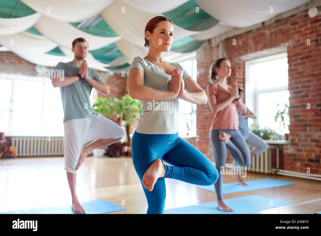 group of people doing yoga tree pose at studio Stock Photo - Alamy