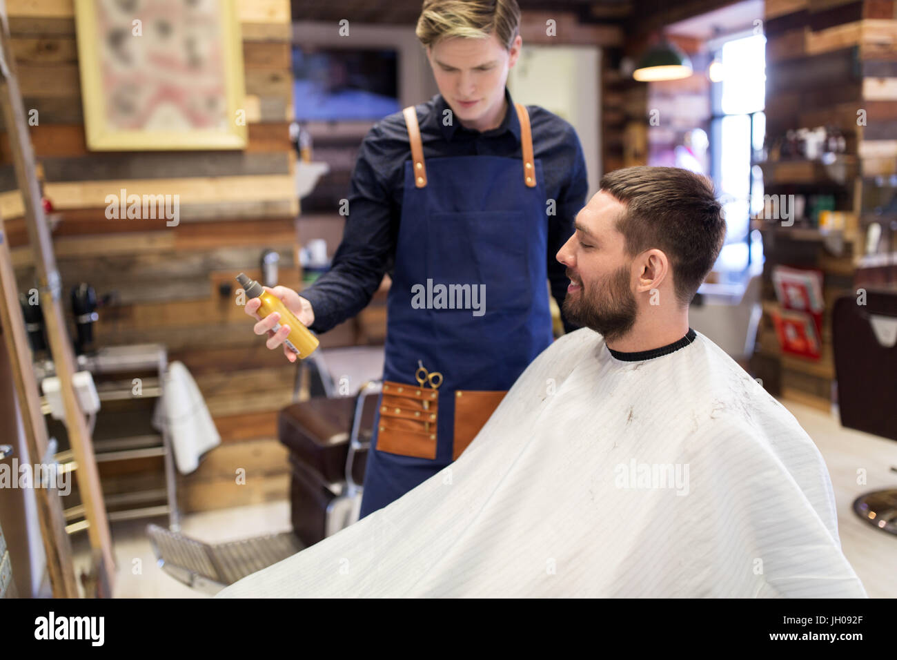 barber showing hair styling spray to male customer Stock Photo