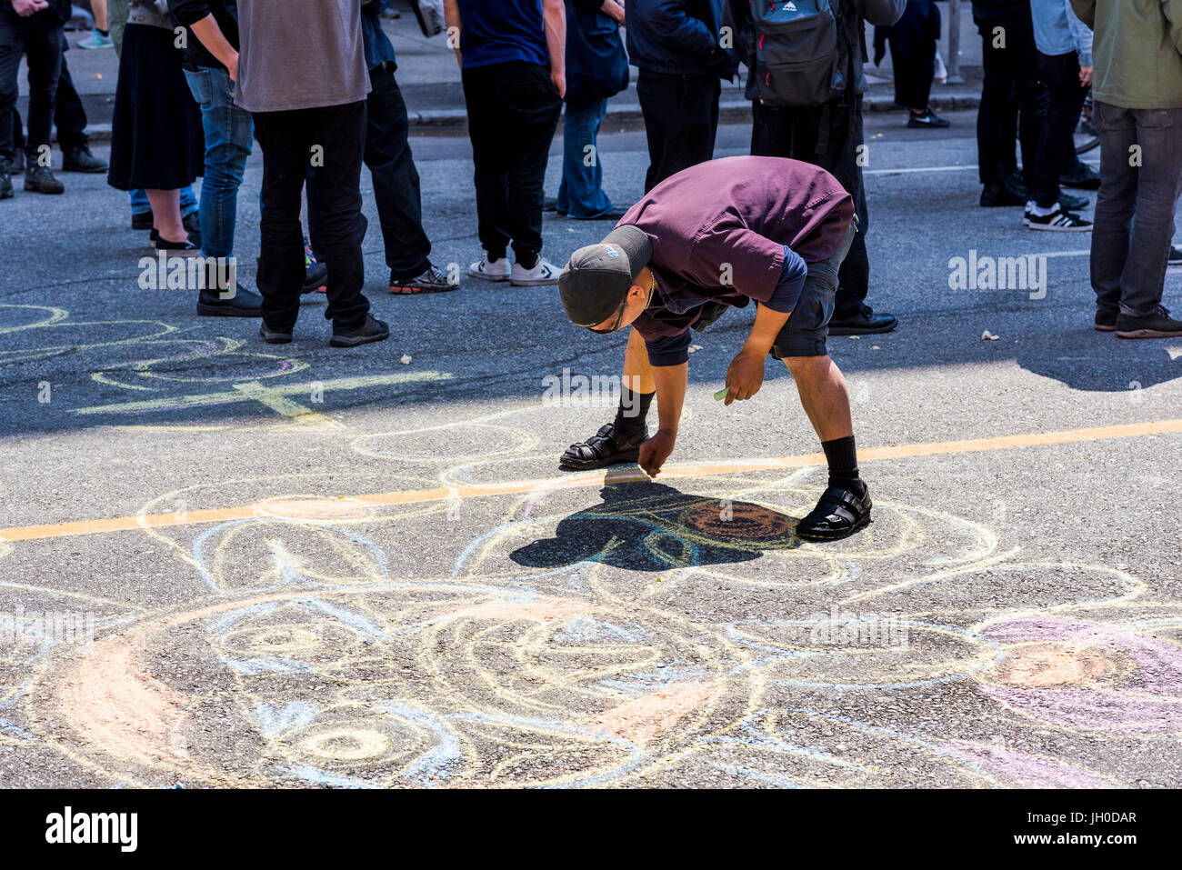 Man creating chalk drawing on road. Balmoral Block Party in support of evicted residents of Downtown Eastside Slum Hotel, Hastings Street, Vancouver,  Stock Photo