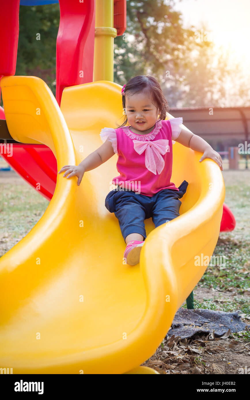 Toddler girl playing on a slide at children playground Stock Photo - Alamy