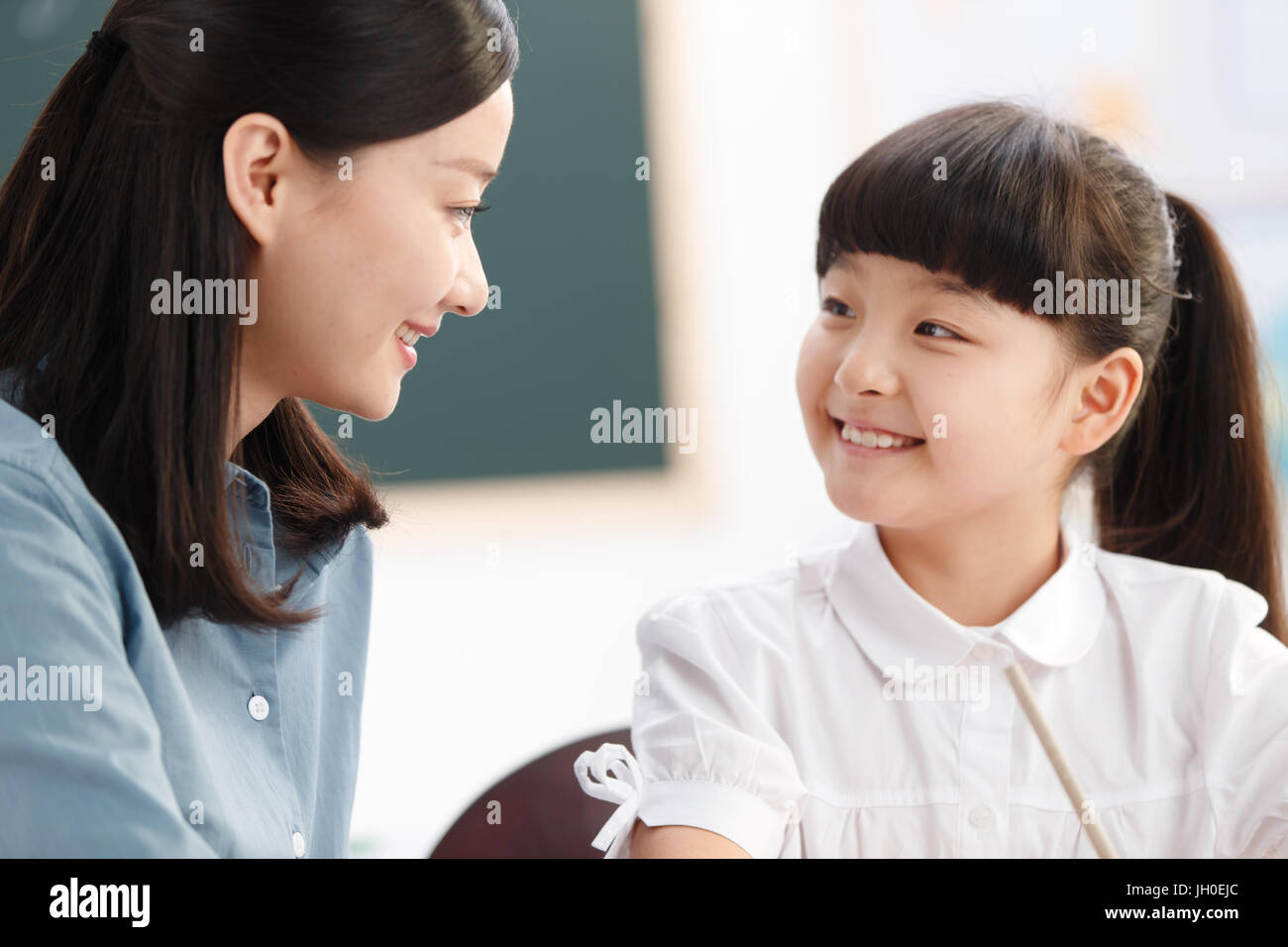 Female teacher helping student studying in classroom Stock Photo