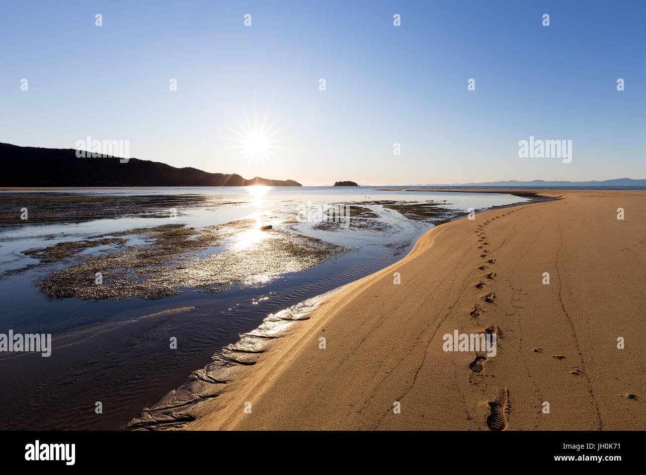 A set of footprints on a sandbar during a bright morning in the Abel Tasman National Park, New Zealand. Stock Photo