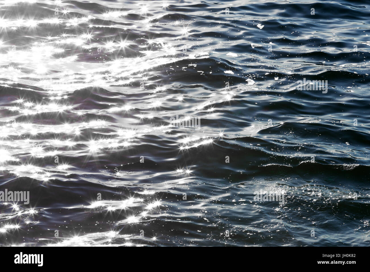 A calm ocean reflects sun stars in the morning light. Stock Photo