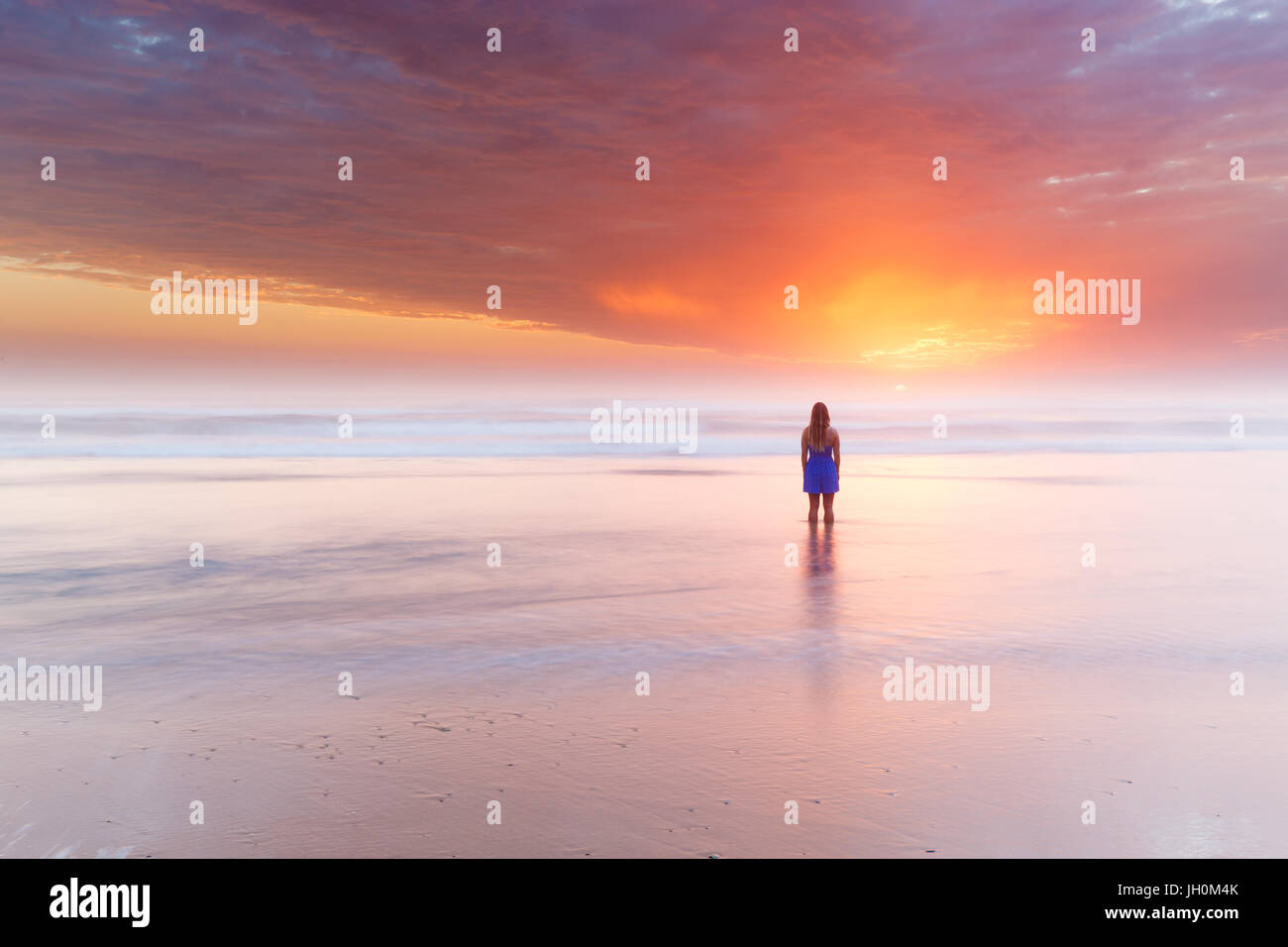 A silhouetted woman watches a beautiful sunrise over the ocean on Australia. Stock Photo