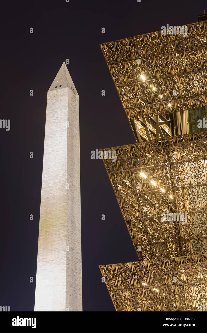 The angular metal architecture of the National Museum of African American History and Culture contrasts with the Washington Monument at night. Stock Photo