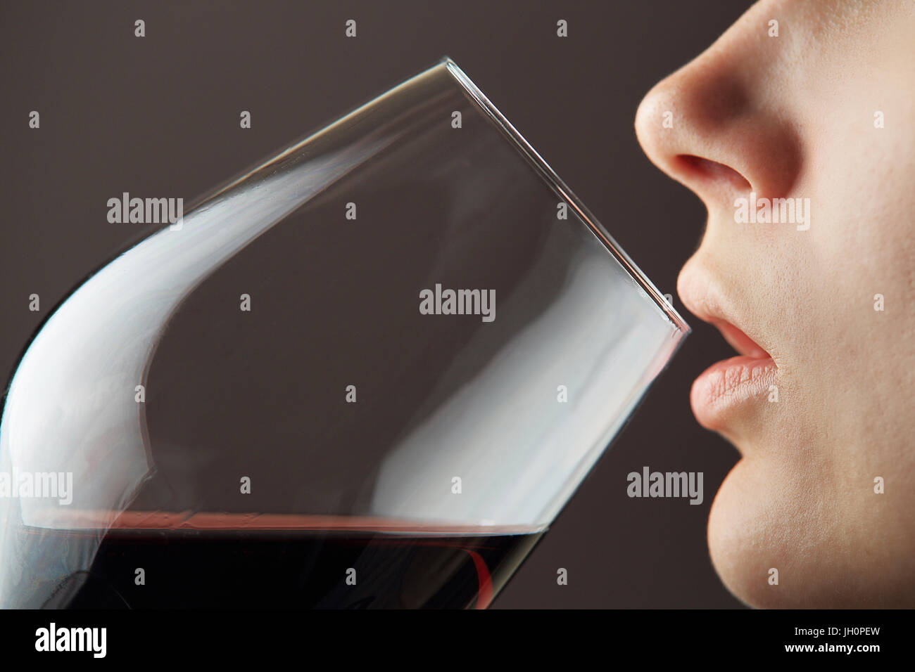 Wine glass with red wine near woman lips. Girl tasting red wine macro