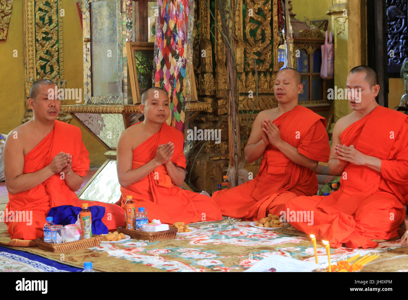 Seated Buddhist monks chanting and reading prayers at a buddhist ceremony. Wat Simuong. Wat Si