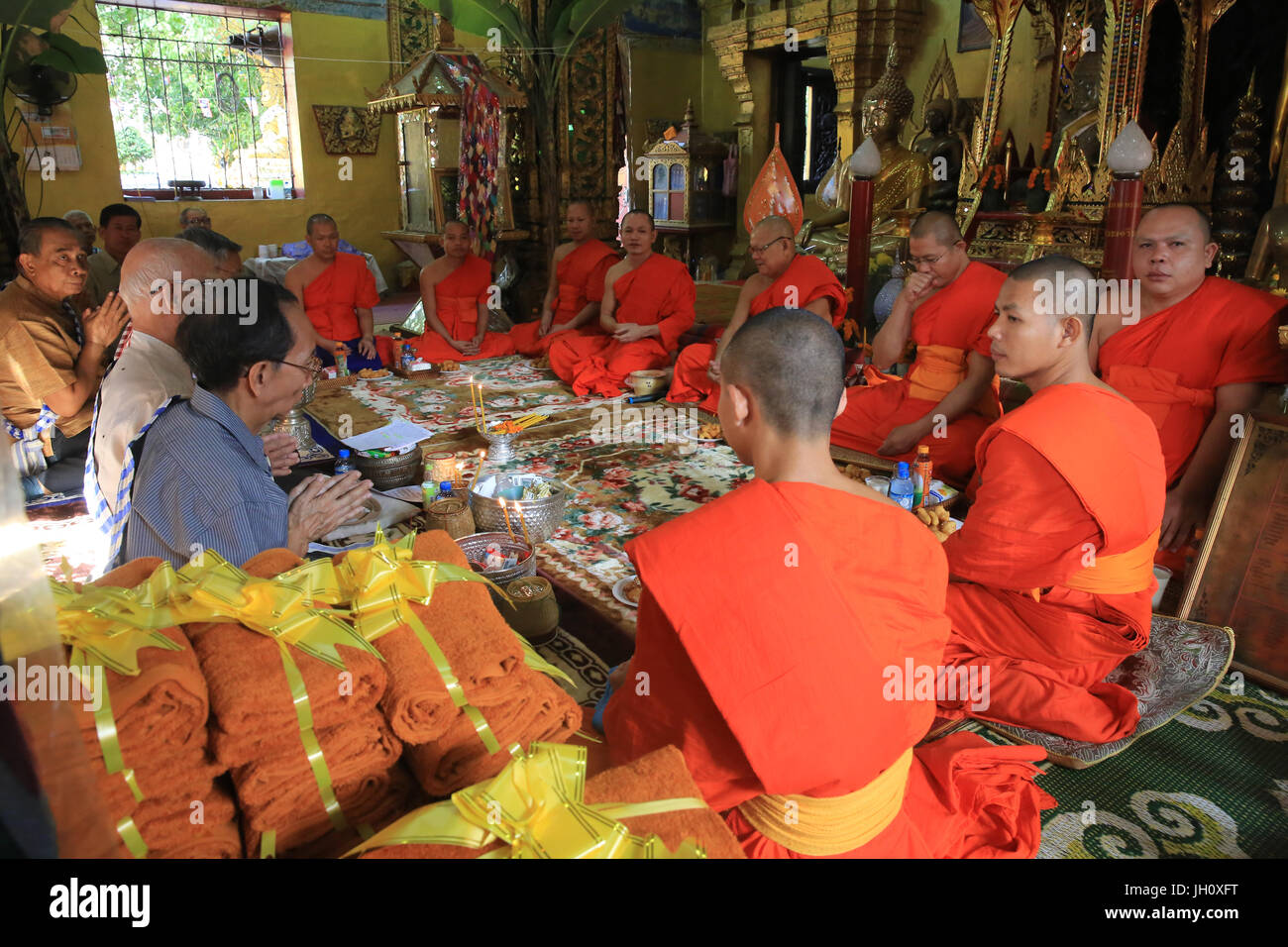 Seated Buddhist monks chanting and reading prayers at a buddhist ceremony. Wat Simuong. Wat Si