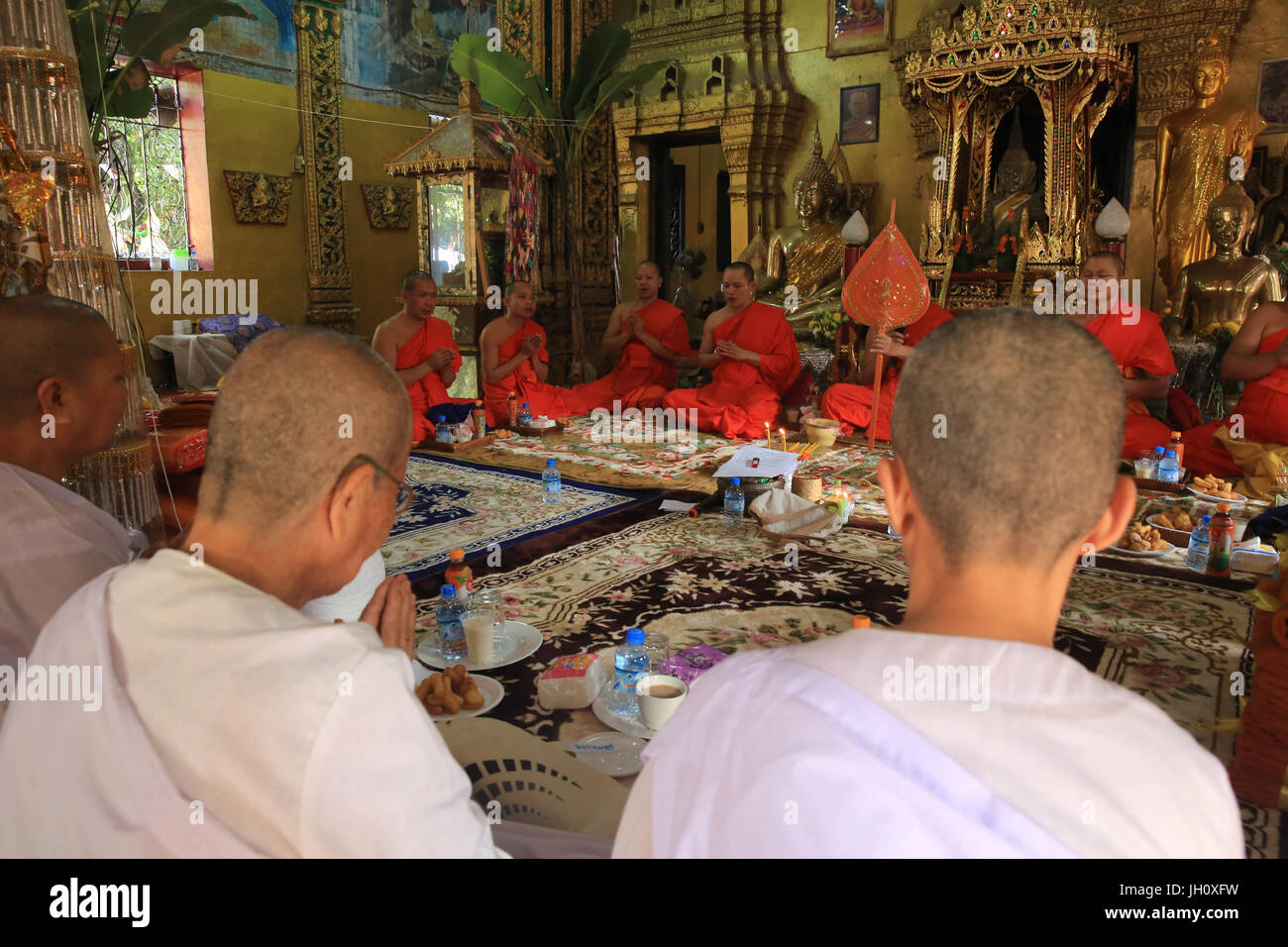 Seated Buddhist monks chanting and reading prayers at a buddhist ceremony. Wat Simuong. Wat Si