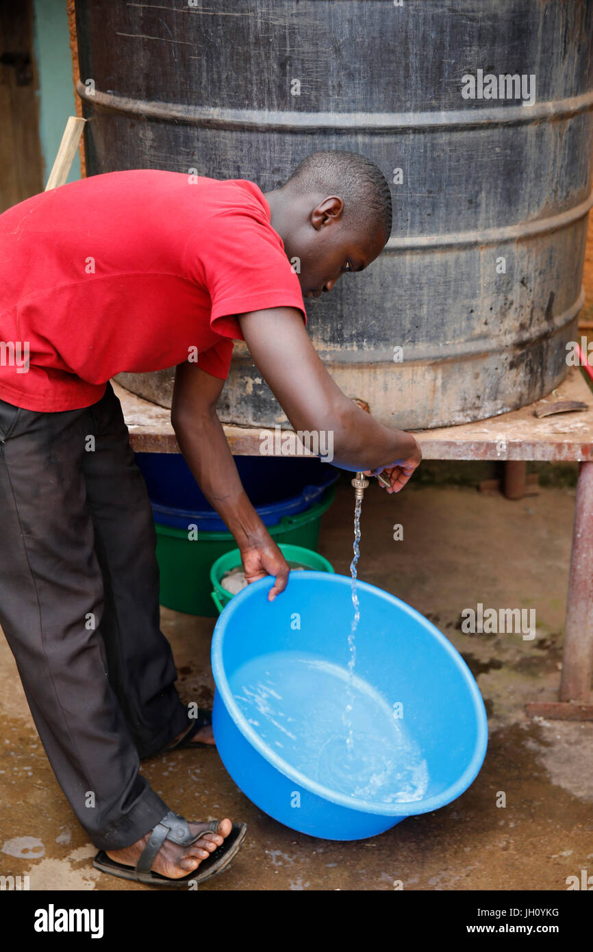 Ugandan using a water tank at mulago parish. Uganda. Stock Photo