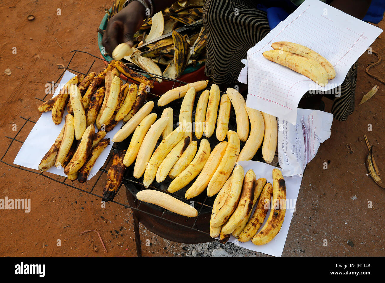Woman making and selling grilled plantain in Mulago. Uganda. Stock Photo