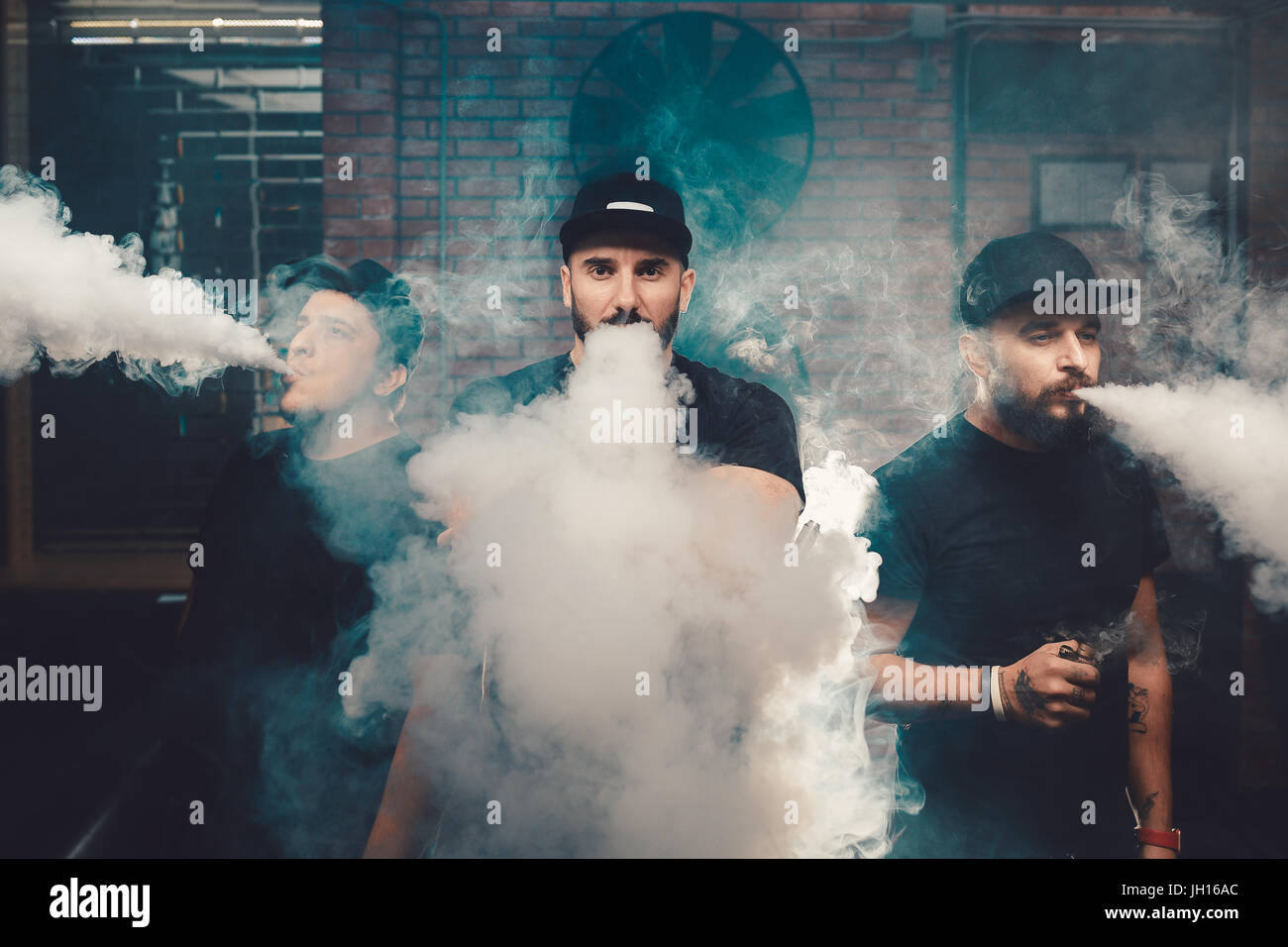 Three men vaping in an authentic room with brick walls. Vaping an