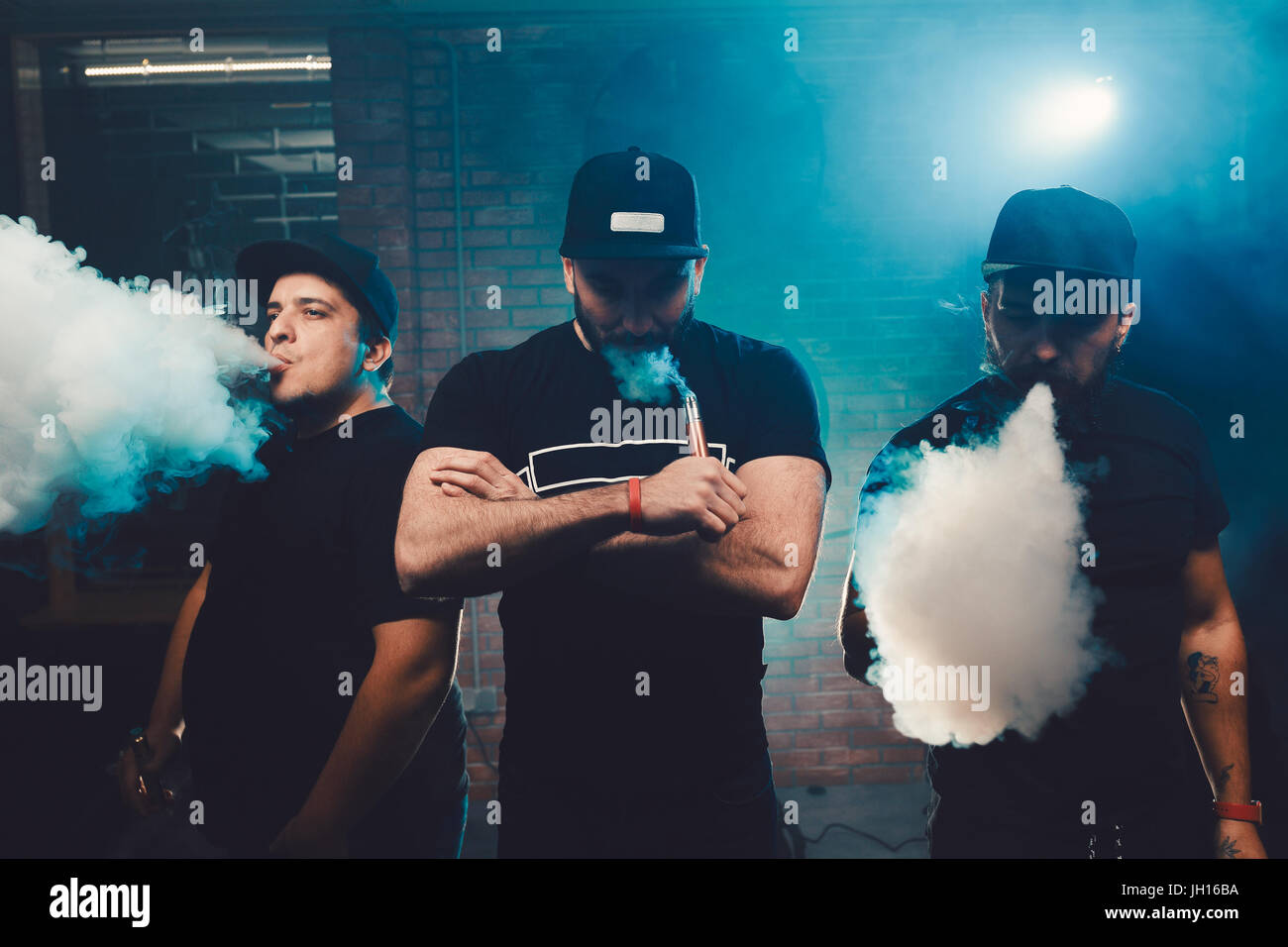 Three men vaping in an authentic room with brick walls. Vaping an