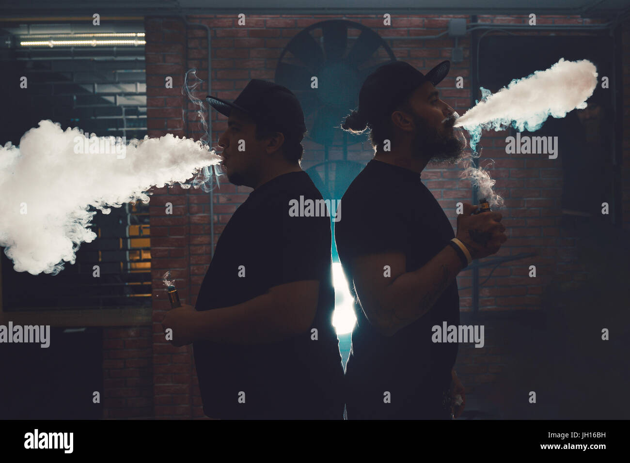 Two men vaping in an authentic room with brick walls. Vaping an