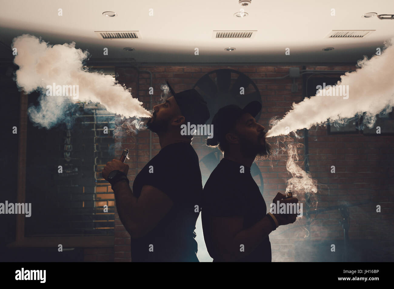 Two men vaping in an authentic room with brick walls. Vaping an