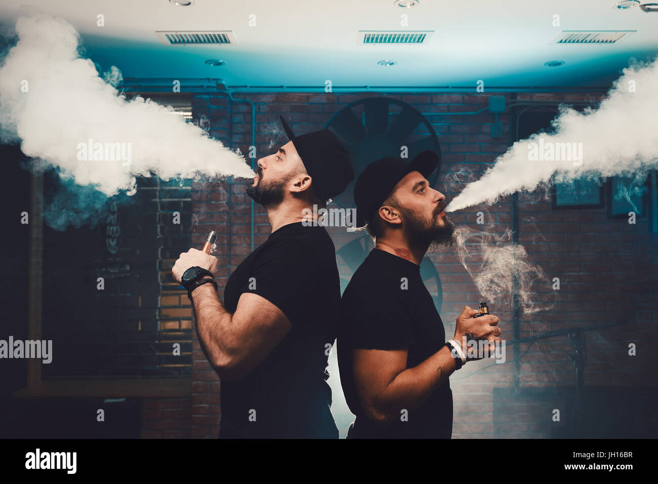 Two men vaping in an authentic room with brick walls. Vaping an