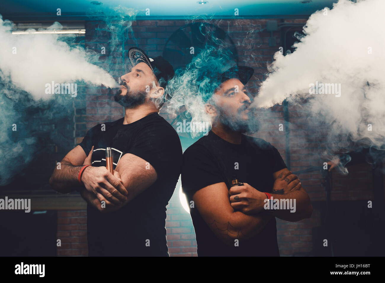 Two men vaping in an authentic room with brick walls. Vaping an
