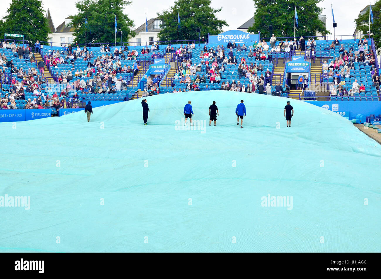 Devonshire Park, Eastbourne. Walking across the covers to remove the air trapped underneath before taking them off centre court after a rain delay... Stock Photo