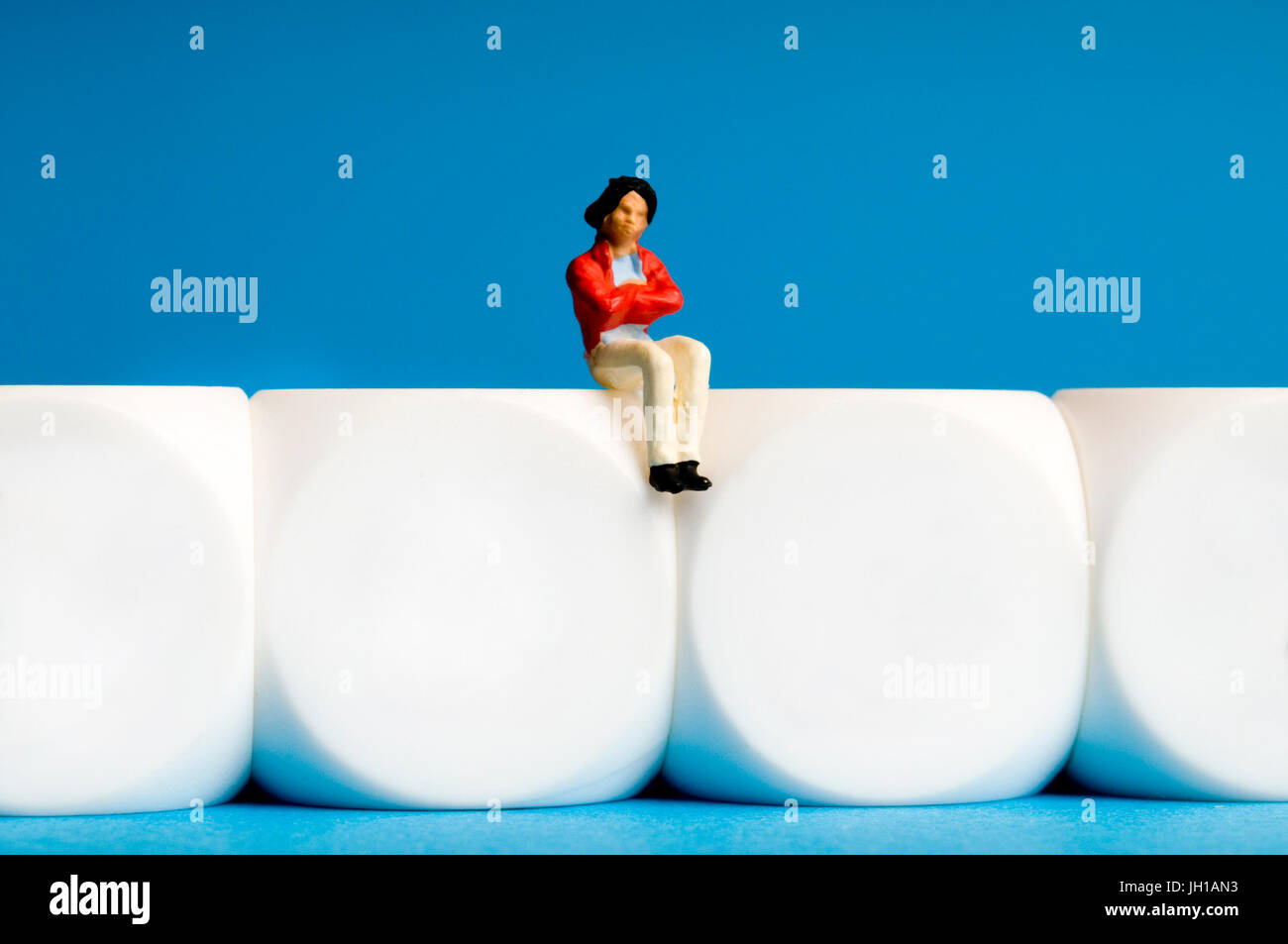 female miniature figurine sitting on white cubes, solitude, psychology and meditation concepts Stock Photo