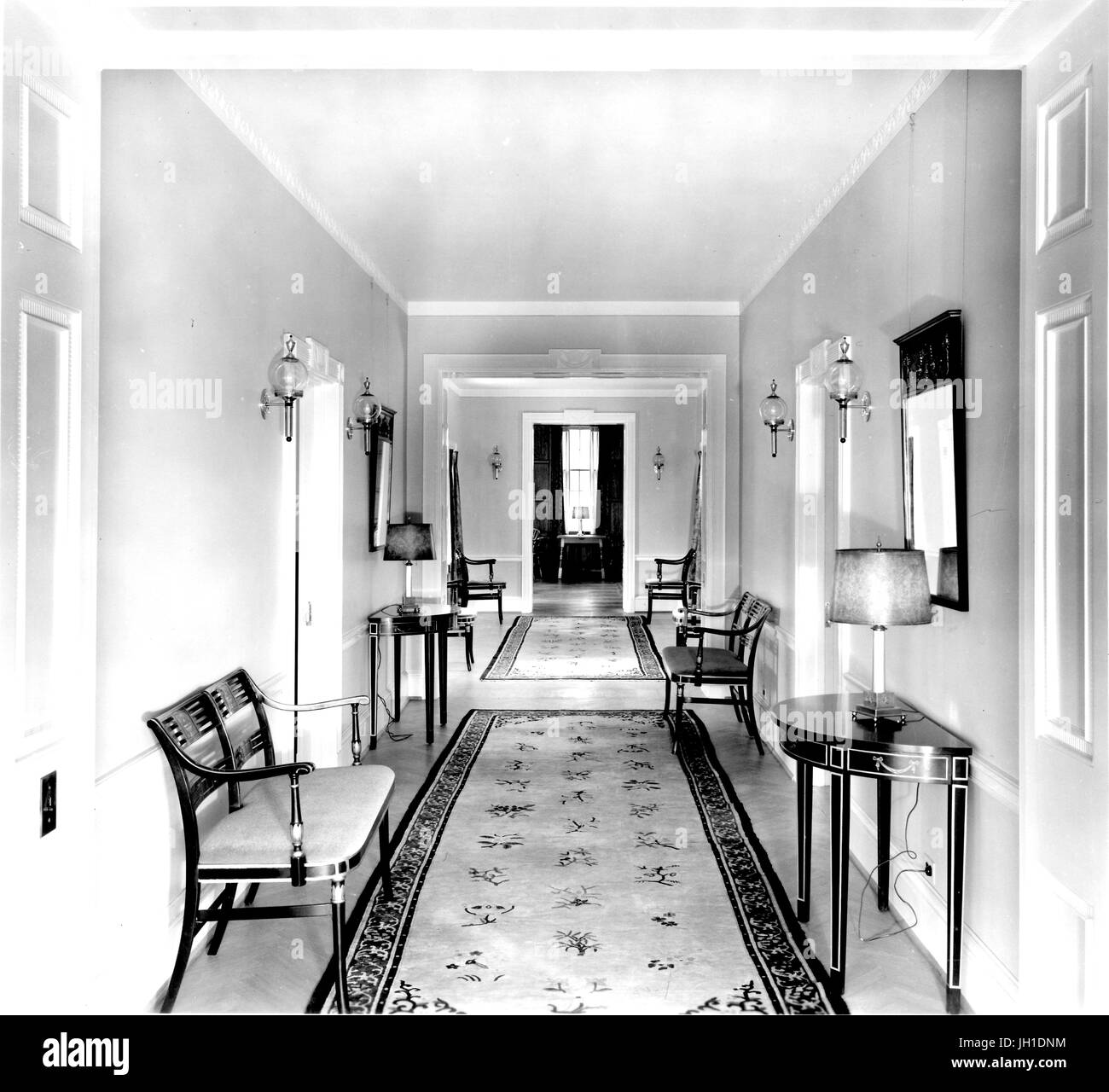Hallway containing decorative carpets, benches, tables, and sconces, in the Johns Hopkins Club, in Baltimore, Maryland, 1930. Stock Photo