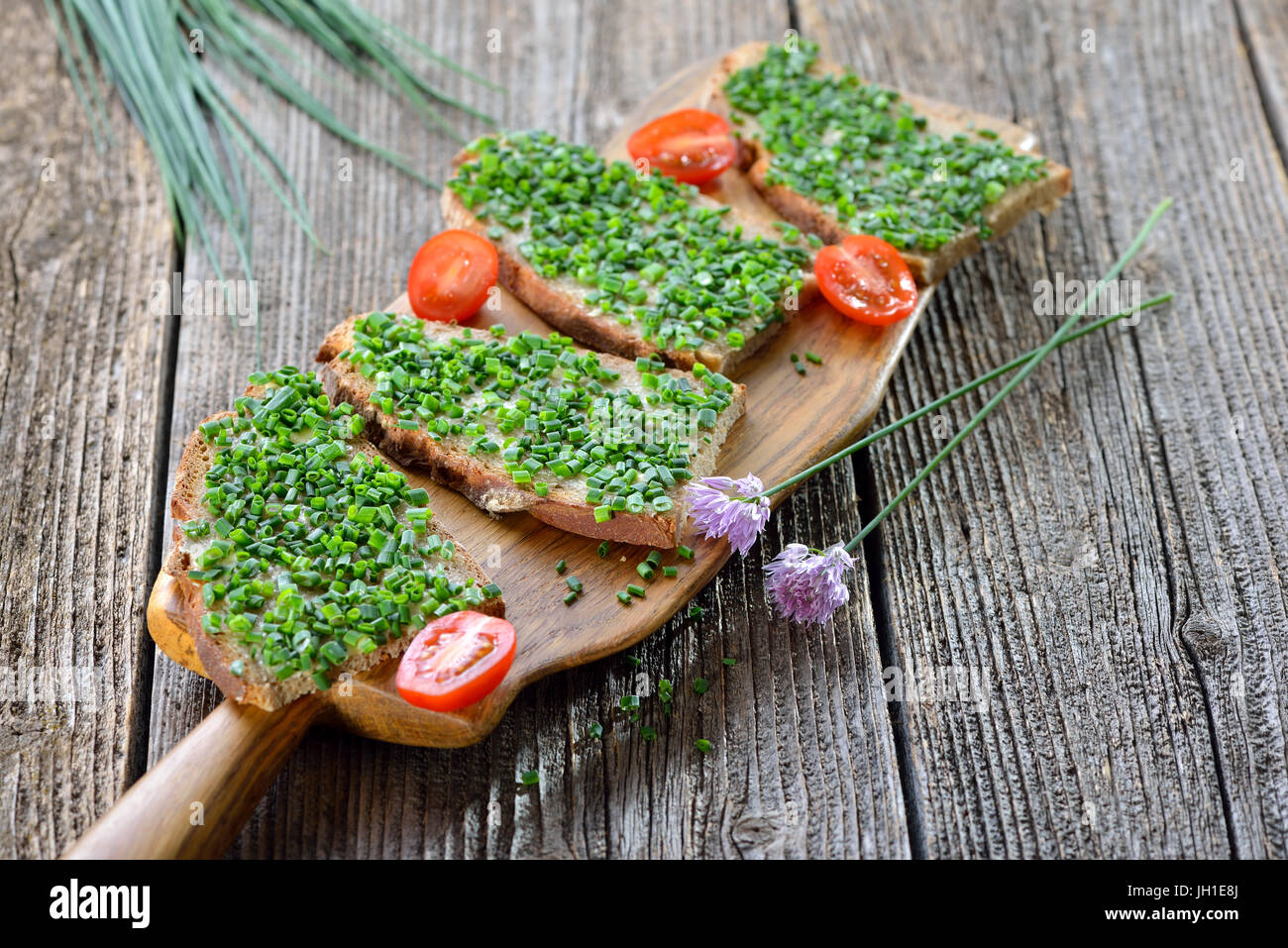 Beer garden food: Slices of fresh farmhouse bread with butter and chopped chives on a wooden board Stock Photo