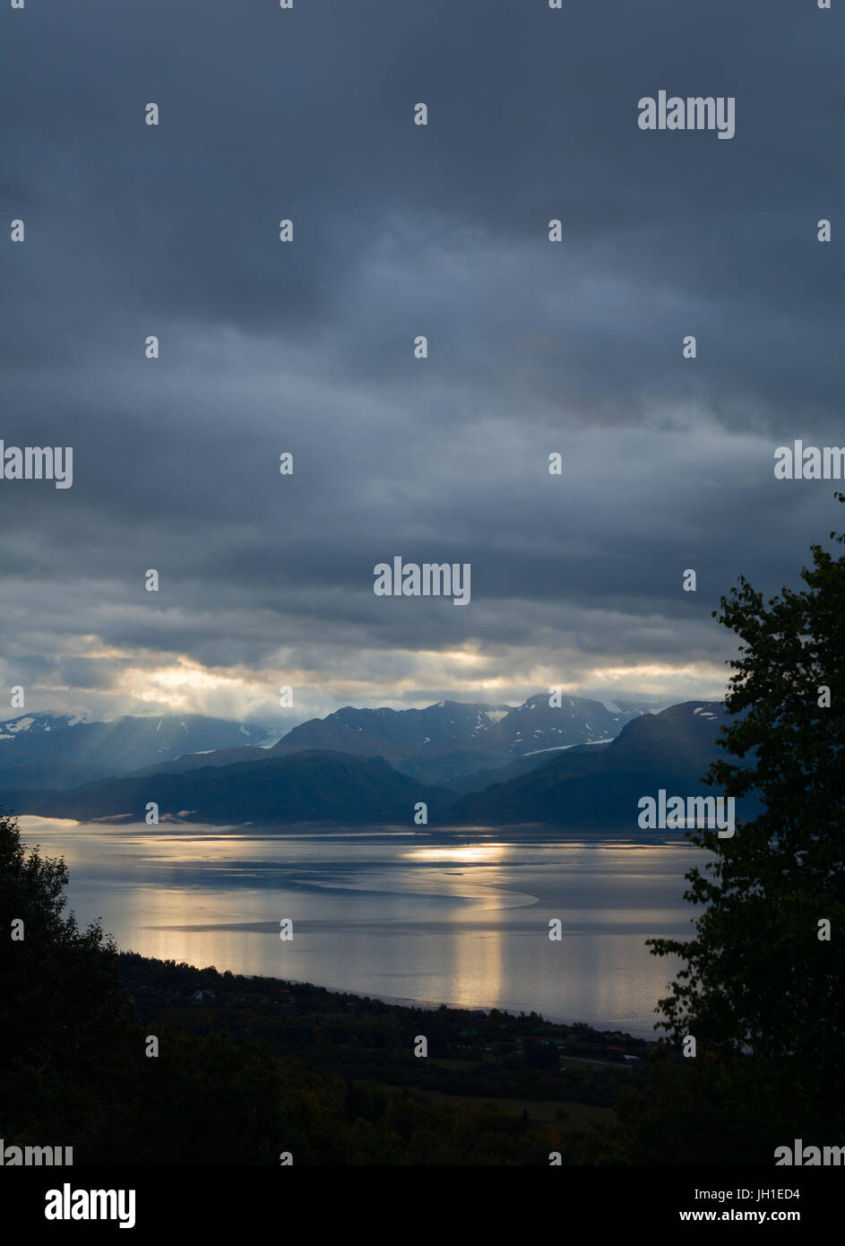 A flat Kachemak Bay acts a perfect mirror for a mostly cloudy sky to reflect off of. Stock Photo