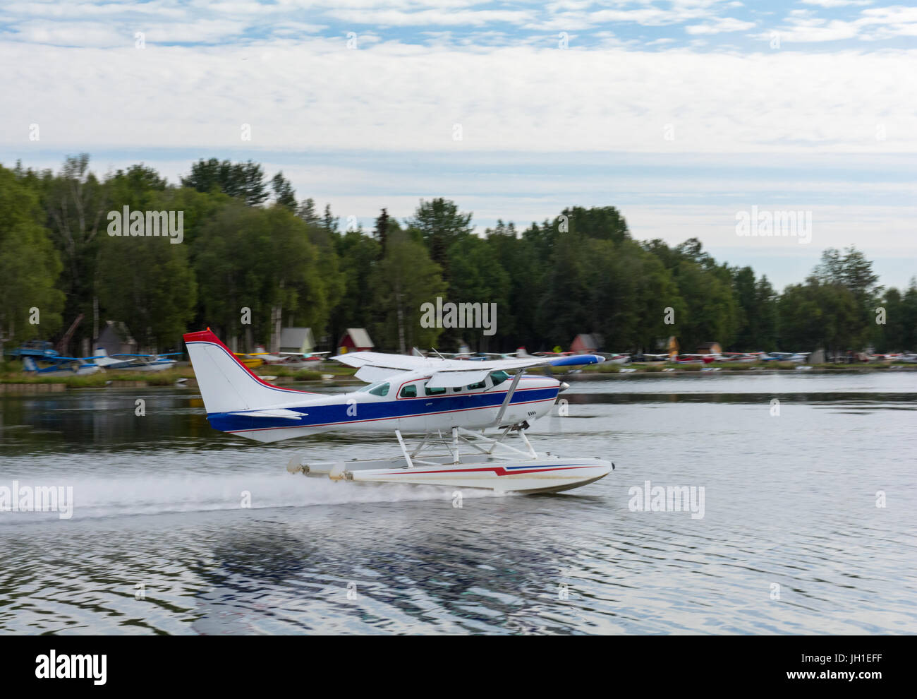 A blue striped sea plane is just touching down at Lake Hood, Anchorage, Alaska. Stock Photo