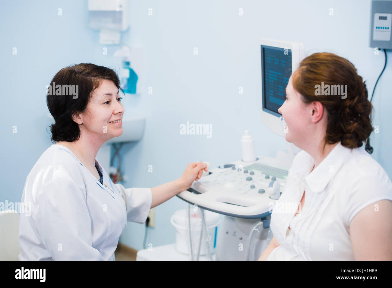 Satisfied pregnant woman having doctor's appointment with ultrasound diagnostics Stock Photo