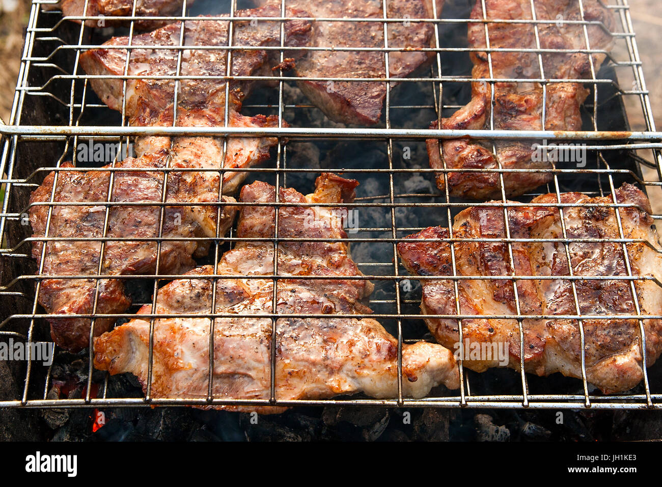 Juicy slices of meat cooking on an open flame grill. Roasted meat with