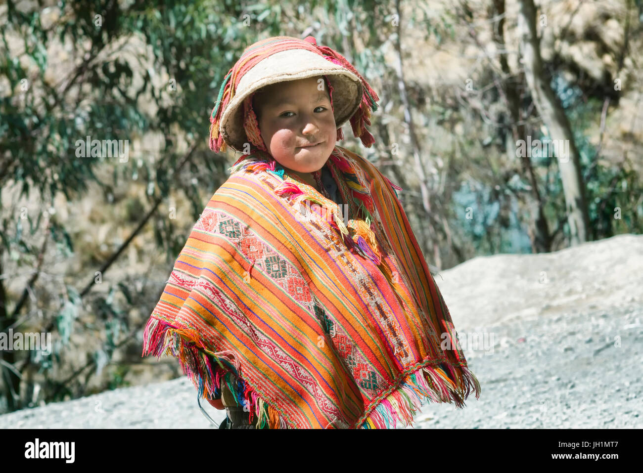Smiling native peruvian boy wearing colorful handmade traditional poncho and a hat. October 21, 2012 - Patacancha, Cusco, Peru Stock Photo