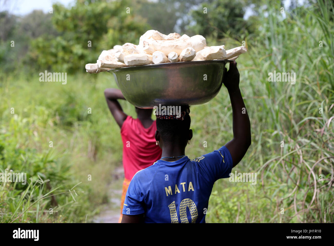 Women carrying platter with cassava on head. Togo. Stock Photo