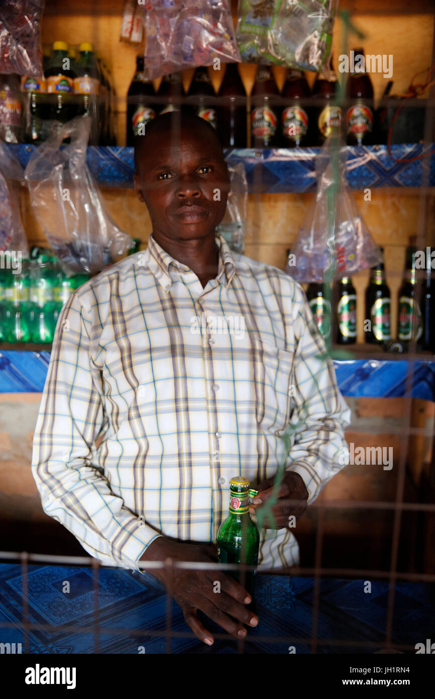 Dennis Openji owns a bar and drink shop in Katulikire. He was able to rent the shop with his first loan from KOLPING (200,000 UGS), bought a solar pan Stock Photo