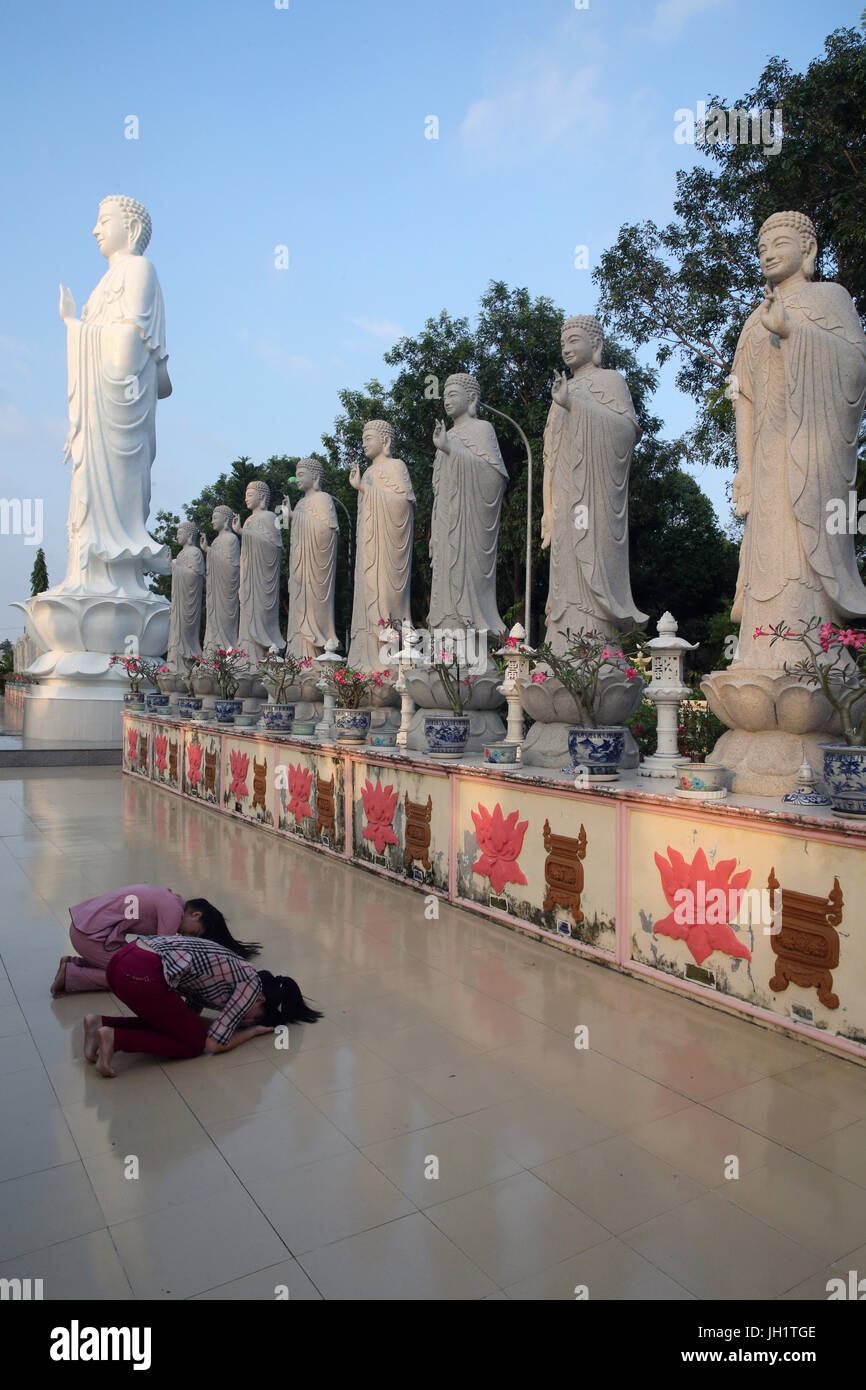 Dai Tong Lam Tu Buddhist Temple.  Woman praying in front of Buddha Amitabha statues.  Ba Ria. Vietnam. Stock Photo