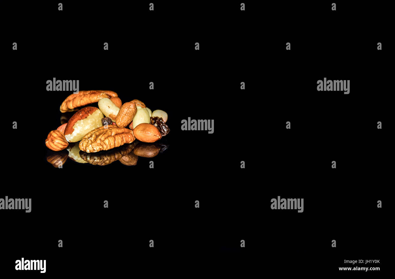 pile of mixed nuts and raisons on black glass Stock Photo