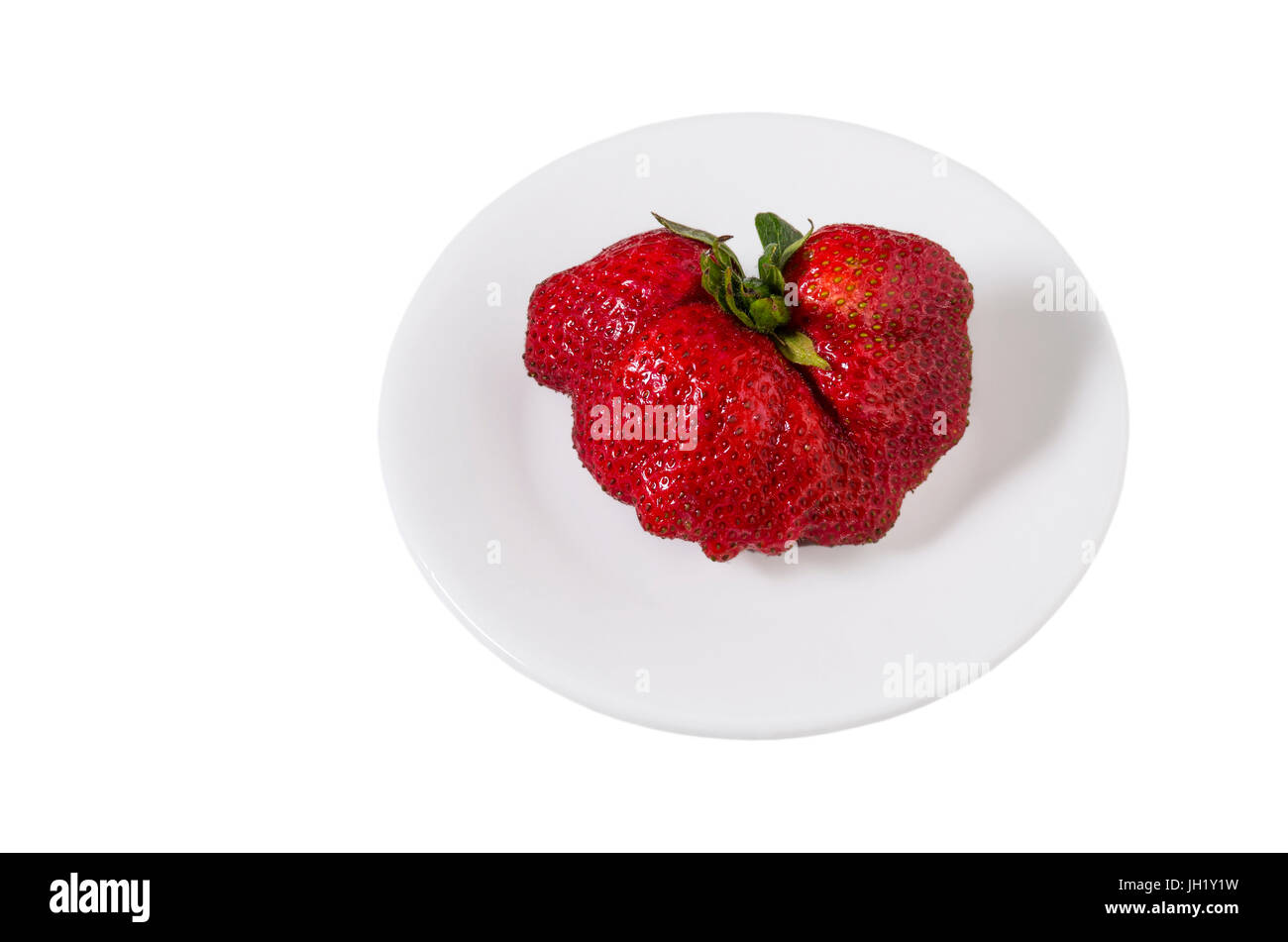Single heart-shaped strawberry isolated on a white dish. Stock Photo