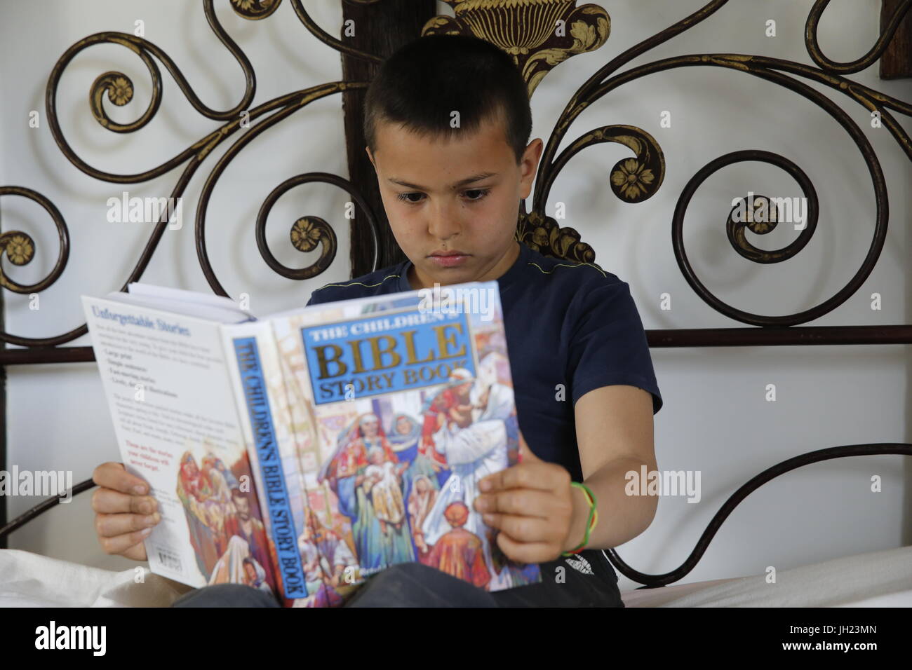 10-year-old boy reading a Bible. France. Stock Photo