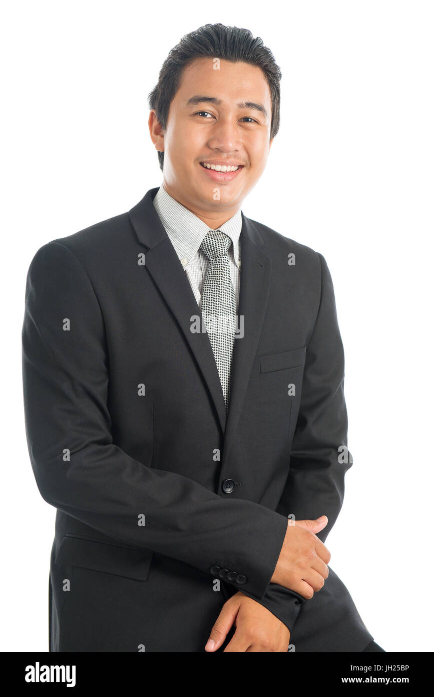 Portrait of happy young Southeast Asian businessman sitting on chair ...