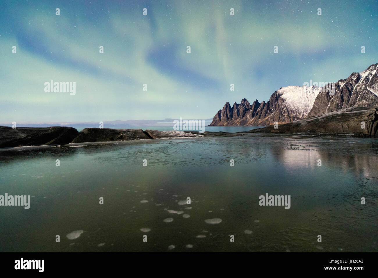The Northern Lights (aurora borealis) and stars reflected in the icy sea, Tungeneset, Senja, Tromo, Norway, Scandinavia, Europe Stock Photo