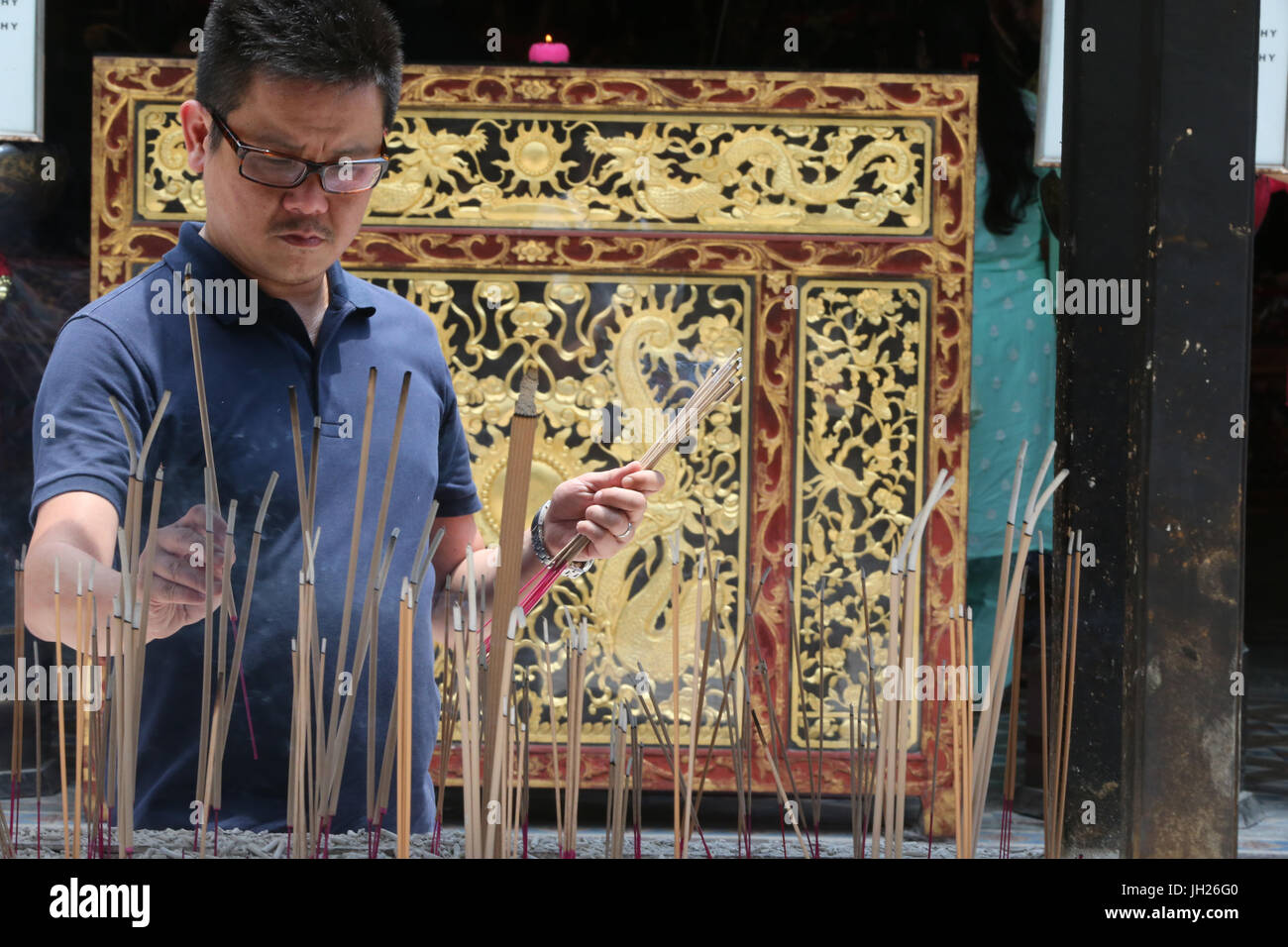 Thian Hock Keng Temple.  A Chinese man praying and offering incense.  Buddhist Worshipper. Burning incense sticks.  Singapore. Stock Photo