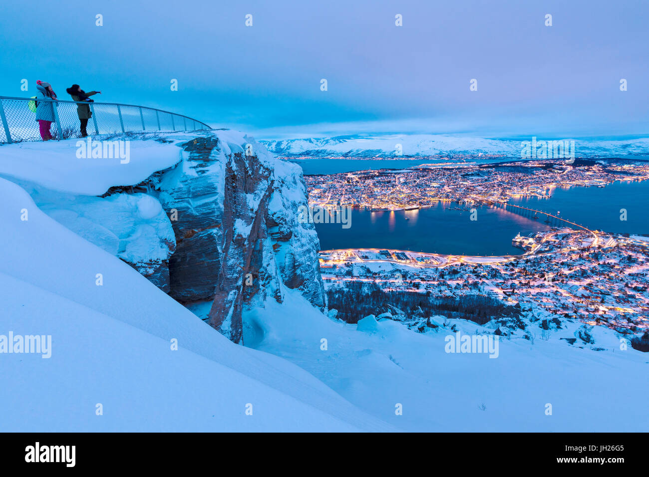 People admire the city of Tromso at dusk from the mountain top reached by the Fjellheisen cable car, Troms, Northern Norway Stock Photo