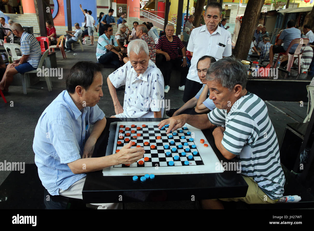 Groups of people congregate to play draughts and other board games on the streets of Chinatown.  Singapore. Stock Photo