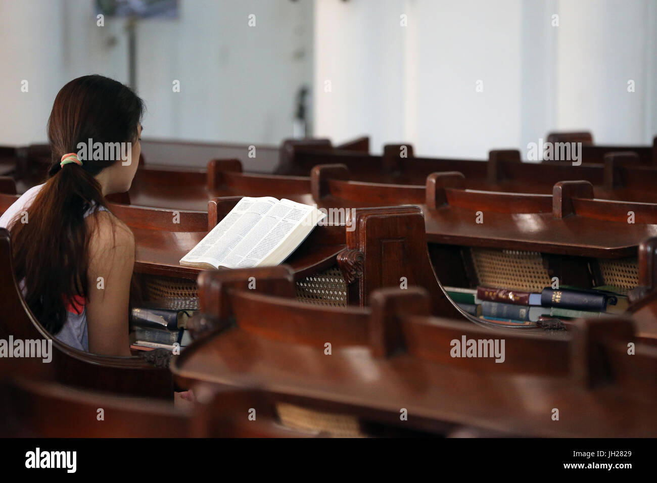 St Andrew's cathedral.  Young woman reading the Holy Bible.  Singapore. Stock Photo