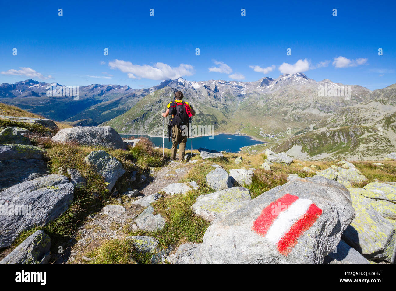 Hiker admires the blue Lake Montespluga and the rocky peaks in summer, Chiavenna Valley, Valtellina, Lombardy, Italy, Europe Stock Photo