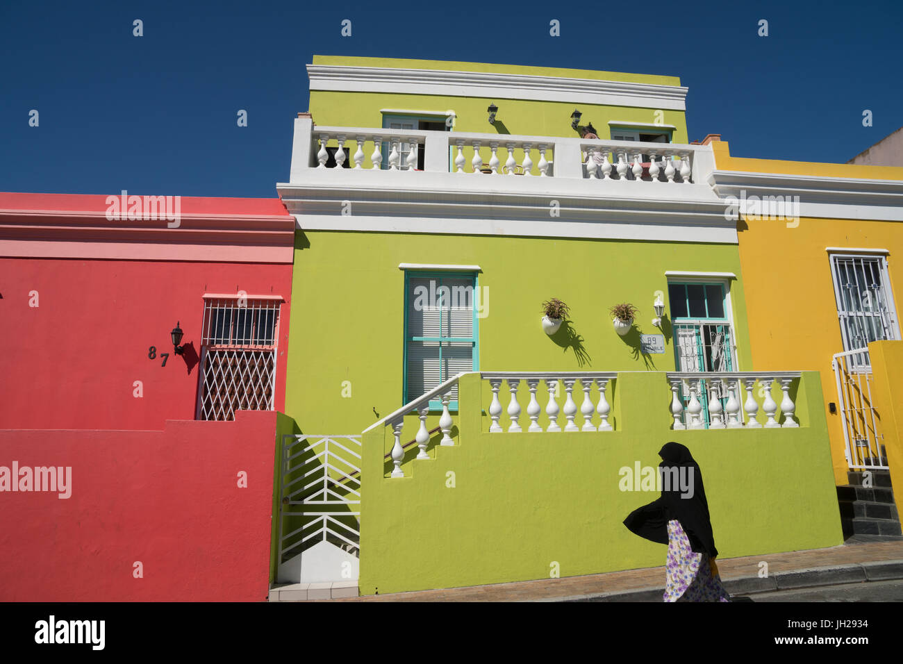 Silhouetted woman covered in black robe passes brightly coloured houses in Bo-Kaap, the Malaysian and Muslim area, Cape Town Stock Photo