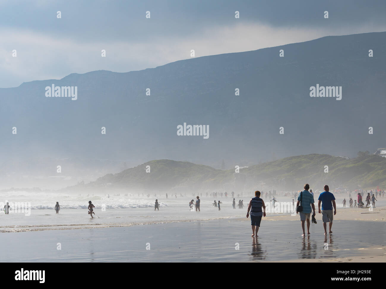 People enjoying walking on the main beach and in the sea in the late afternoon light, Hermanus, South Africa, Africa Stock Photo