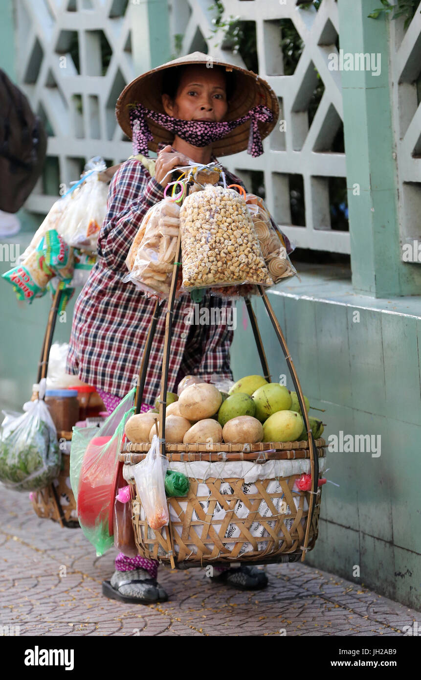 A woman vendor carries her fruit produce in baskets. Ho Chi Minh City. Vietnam. Stock Photo